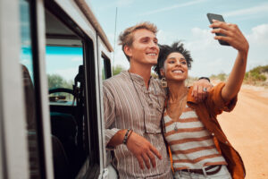 Young couple who retired early taking a selfie by their vehicle wile on safari