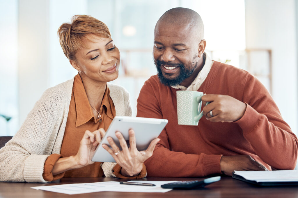 Middle aged family planning their retirement together in front of their laptop with coffee in a sunny kitchen