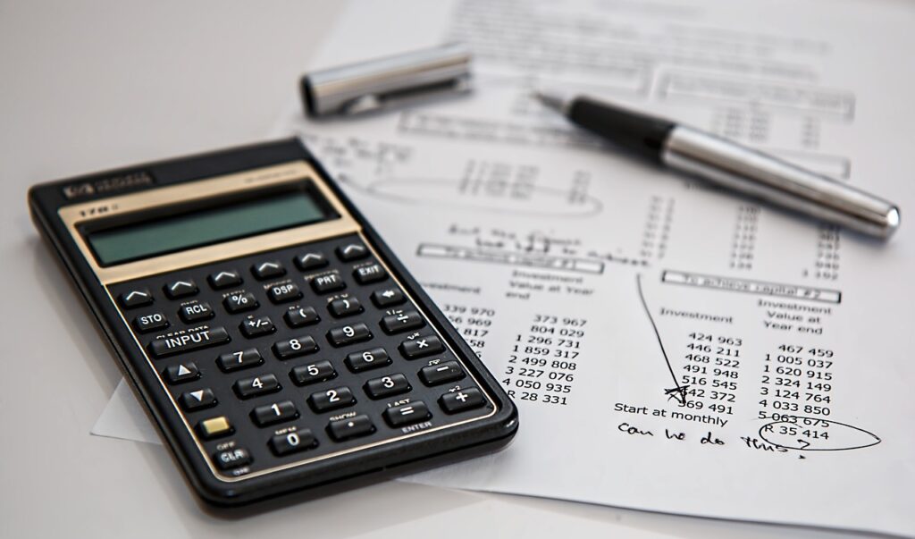 A close-up shot of a calculator sitting on top of an insurance bill. In the background, a pen sits uncapped.