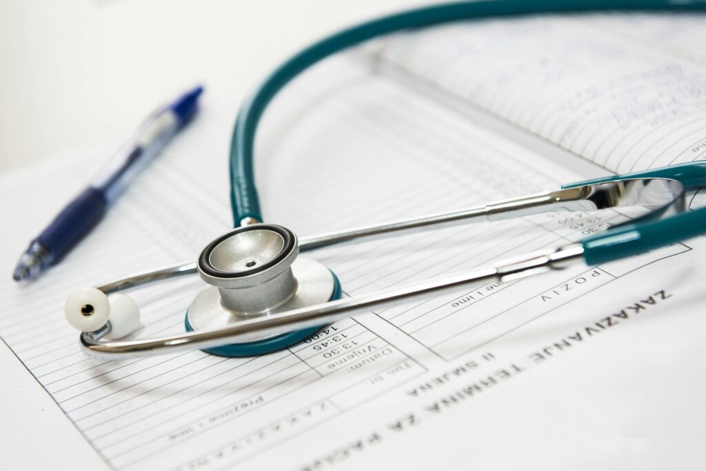 A close-up shot of a stethoscope sitting on top of a sign-in sheet. A blue pen sits in the background.