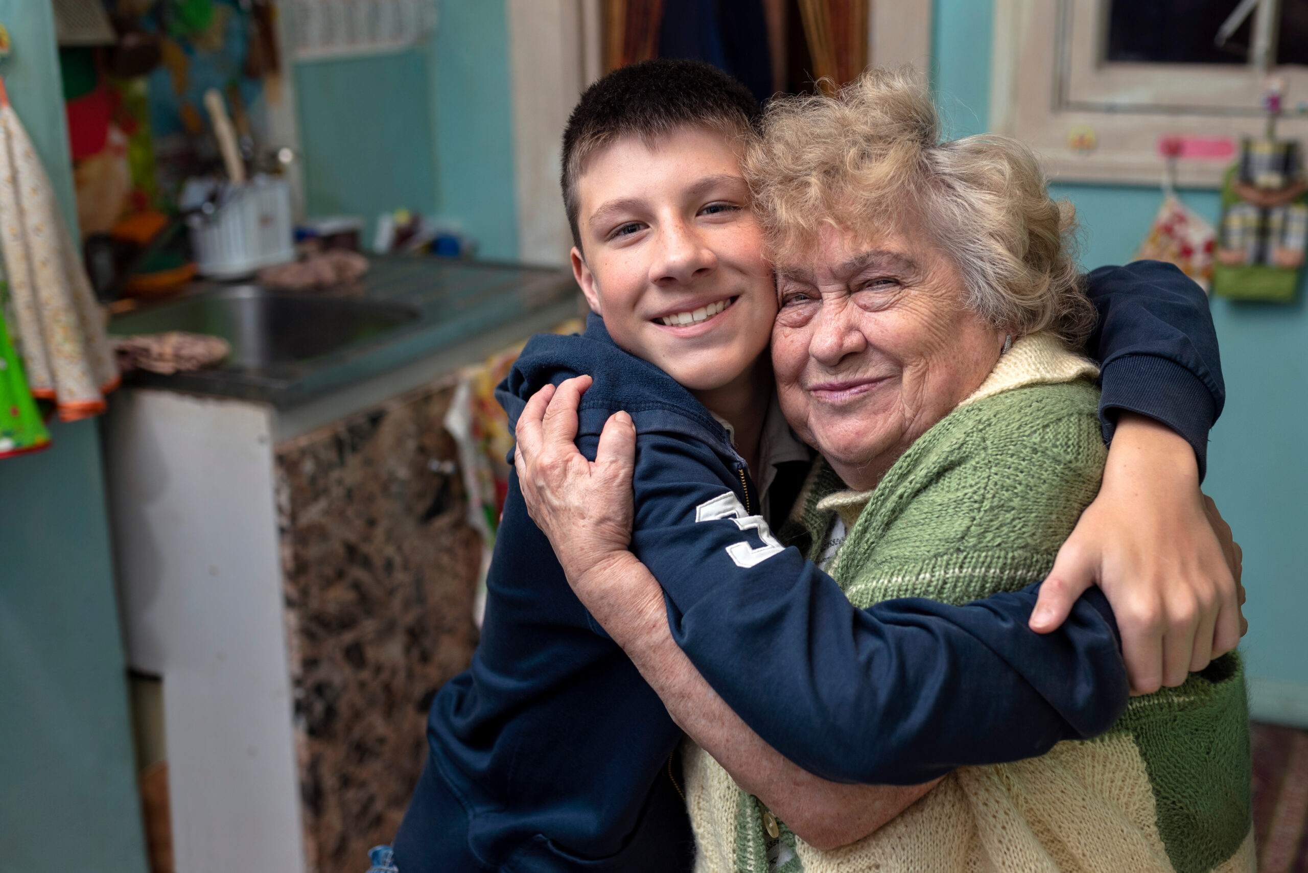 Senior on a fixed income hugging grandson happily looking at viewer